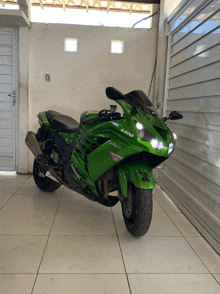 a green kawasaki motorcycle is parked in front of a garage