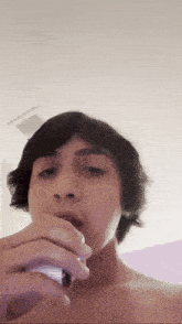 a young man is singing into a microphone without a shirt on