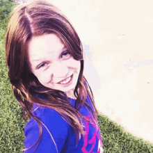 a young girl wearing a blue shirt with the letter g on it smiles