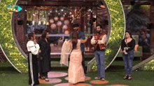 a group of people are standing in front of a green wall that says extra live channel