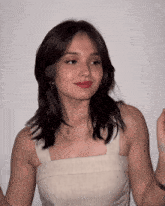 a woman wearing a white tank top with a necklace that says ' a ' on it