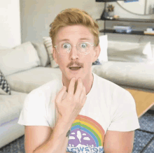 a man wearing glasses and a t-shirt with a rainbow on it is making a funny face