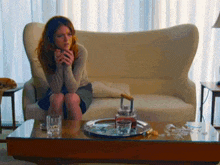 a woman is sitting on a couch next to a table