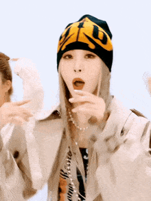 a woman wearing a beanie and a trench coat is making a surprised face .