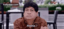 a man is sitting at a table with his arms crossed and says " avuna ... "