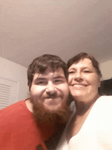 a man with a beard and a woman are taking a selfie together .