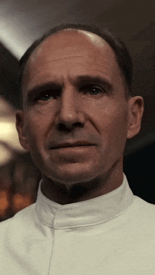 a close up of a man 's face with a white shirt on