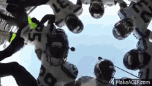 a group of football players are standing in a huddle looking up at the sky .