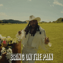 a man in a cowboy hat is dancing in a field with the words bring on the pain behind him