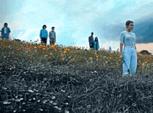 a group of people are standing on top of a field of flowers