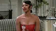 a woman in a red strapless dress is sitting on a couch with her mouth open