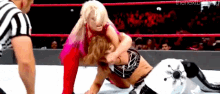 two women are wrestling in a wrestling ring with a referee watching .