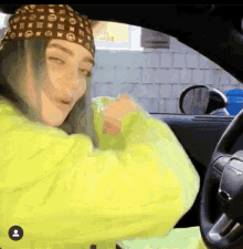 a woman wearing a louis vuitton headband and a yellow jacket is sitting in a car