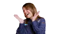 a woman wearing a blue shirt is laughing with her hands in the air