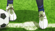 a soccer player kicks a soccer ball on a field with the word touma in the corner