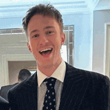 a man in a suit and tie smiles with his mouth wide open