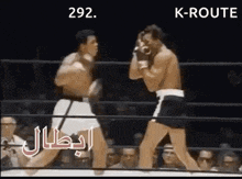 two men are fighting in a boxing ring while a crowd watches .