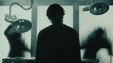 a silhouette of a person standing in front of surgical lights
