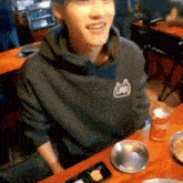 a man wearing a black lmr sweatshirt is sitting at a table