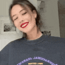 a woman wearing a blue sweater and red lipstick is smiling .