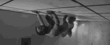 a man is hanging upside down from the ceiling of a room .