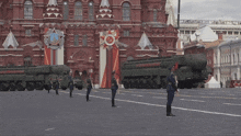 a military parade is taking place in front of a building that has a medal on it