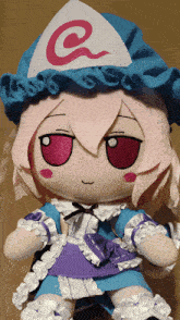 a stuffed doll with pink hair and a blue hat with a letter g on it