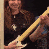 a woman is playing an electric guitar with a scream shirt on