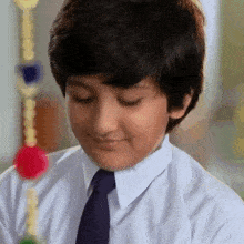 a young boy wearing a white shirt and tie is looking down .