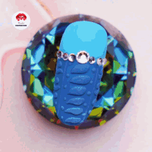 a blue object with rhinestones on it sits on top of a diamond shaped item