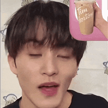 a close up of a person 's face with a cup that says tim hortons