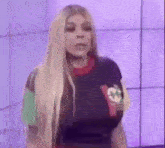 a woman with long blonde hair is wearing a colorful shirt .