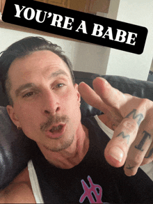 a man laying on a couch with a sign that says you 're a babe above him