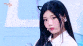 a girl with long black hair is wearing a white shirt and a cat ear .