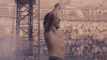 a man without a shirt is standing in front of a crowd .