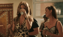a woman in a leopard print dress is drinking from a white cup