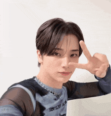 a young man giving a peace sign wearing a blue shirt with the word jeep on it