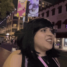 a woman is smiling in front of a building with a sign that says ' a ' on it