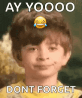 a young boy is laughing with a smiley face on his head and the words `` ay yoooo dont forget '' .