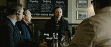 a group of men are sitting at a table in front of a menu that says ' burgers ' on it