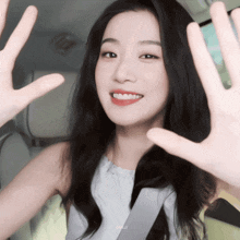 a woman in a white shirt is smiling and making a hand gesture