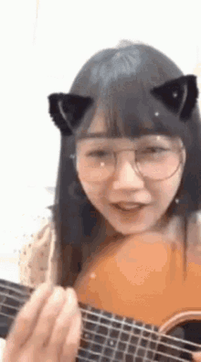 a girl with glasses and cat ears is playing a guitar