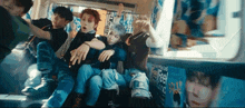 a group of young men are sitting on a bus with posters on the side .