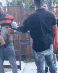 a group of men are standing on a sidewalk and one of them is holding a can of soda