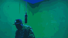 a man wearing a ny hat stands in front of a green wall