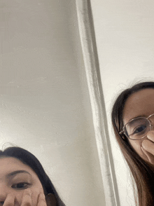 two women wearing glasses are covering their faces with their hands