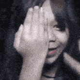 a woman is covering her face with her hand .