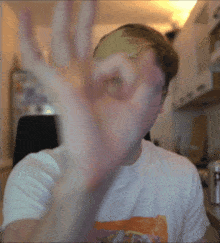 a man in a white shirt is making an ok sign with his hand