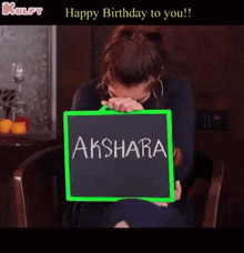 a woman covering her face while holding a sign that says aksara