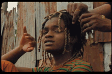 a man with dreadlocks is getting his hair braided by another man